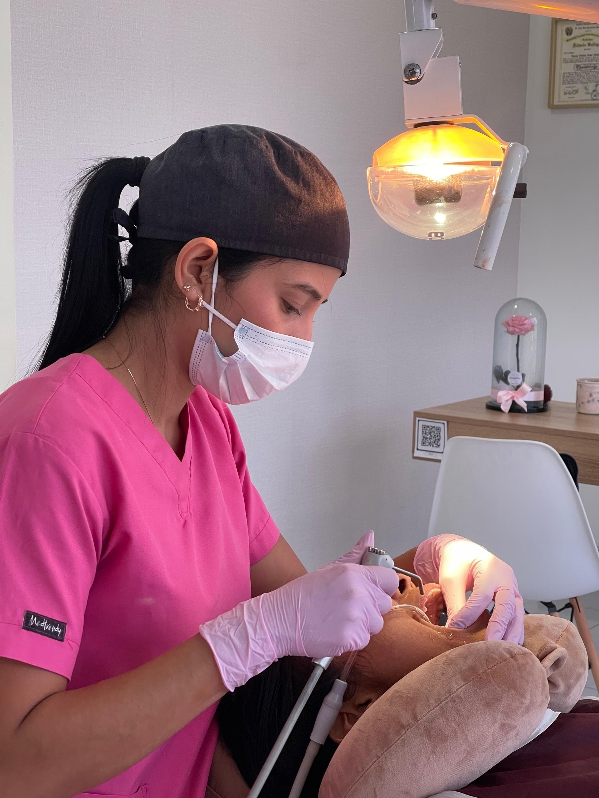 La Od. Sayl Molina trabaja con instrumental en la boca de un paciente recostado en el sillón dental